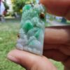 a hand holding a jade pendant