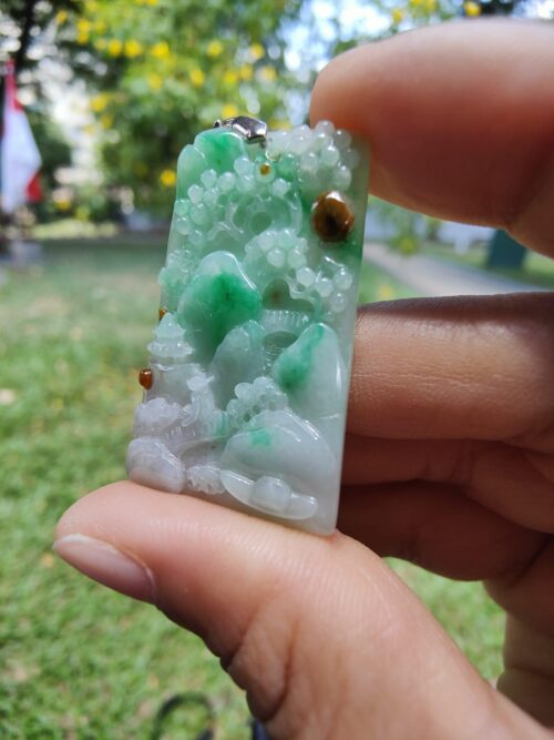 a hand holding a jade pendant