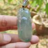 Una mano sosteniendo un colgante de jade.
