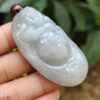 a hand holding a jade pendant