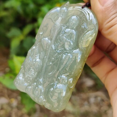a hand holding a jade pendant