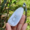 a hand holding a jade pendant