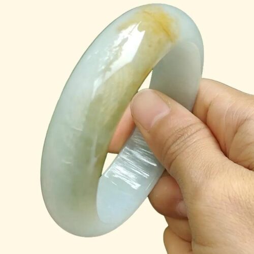 एक हाथ में सफ़ेद और हरा कंगन पकड़े हुए