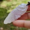 a hand holding a white jade bird pendant