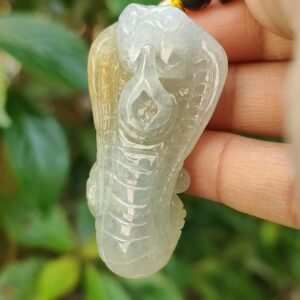 a hand holding a jade snake pendant