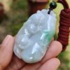 a hand holding a jade pendant
