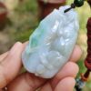 a hand holding a jade pendant
