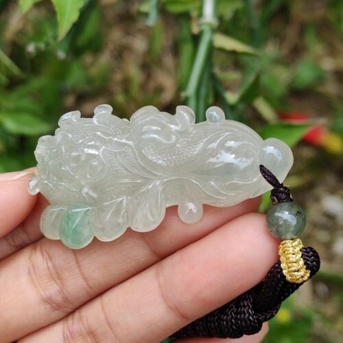 uma mão segurando um pingente de jade