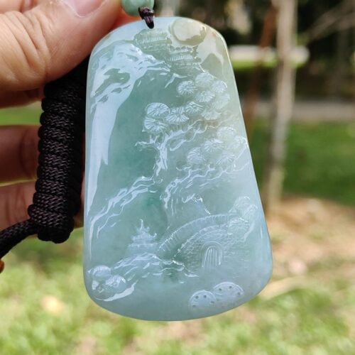 a hand holding a jade pendant