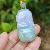 a hand holding a jade pendant