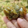 Una mano sosteniendo un pequeño animal de piedra verde.