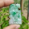 a hand holding a jade pendant