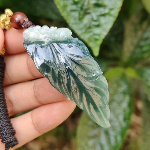 a hand holding a green leaf pendant