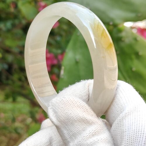 a hand wearing white glove holding a white ring