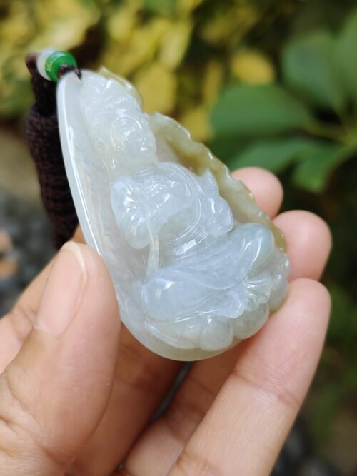 a hand holding a jade pendant