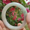a hand holding a white circular bracelet