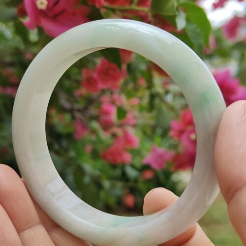 a hand holding a white circular bracelet