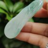 a hand holding a jade pendant