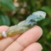 a hand holding a jade leaf pendant