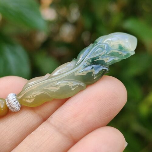 a hand holding a jade leaf pendant