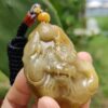 a hand holding a jade pendant