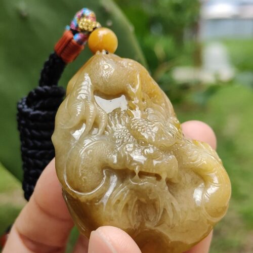 a hand holding a jade pendant