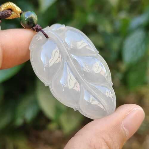 a hand holding a jade leaf necklace