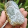 a hand holding a jade pendant