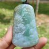 a hand holding a jade pendant