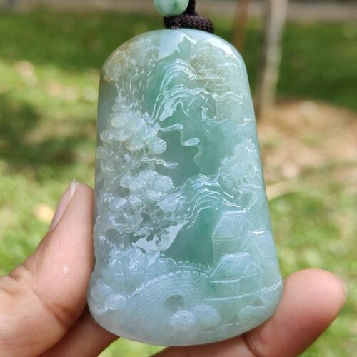 a hand holding a jade pendant