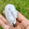 Una mano sosteniendo un colgante de jade blanco.