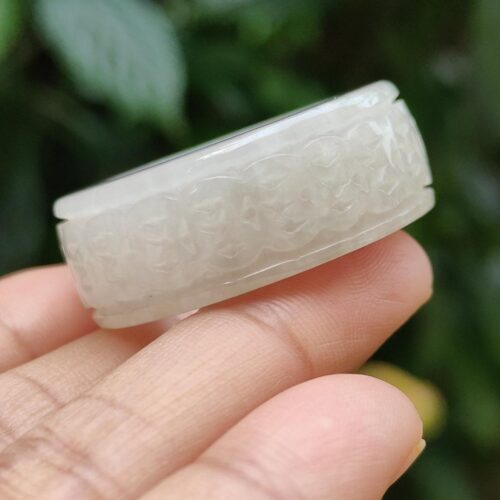 a hand holding a carved ring