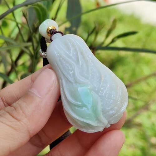 ஜேட் பதக்கத்தை வைத்திருக்கும் ஒரு கை