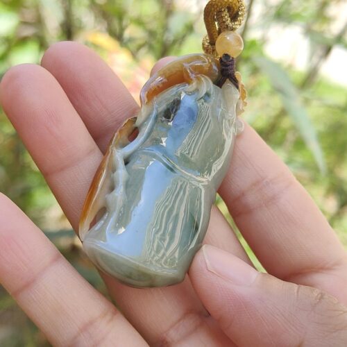 Una mano sosteniendo un colgante de jade.