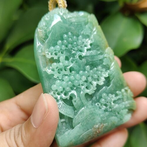 a hand holding a jade pendant