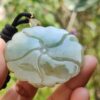 a hand holding a jade pendant