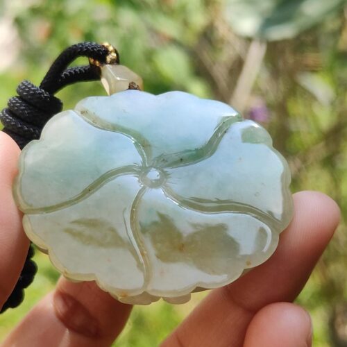 a hand holding a jade pendant