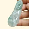 a hand holding a jade pendant