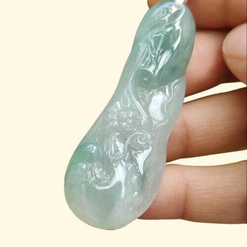 a hand holding a jade pendant