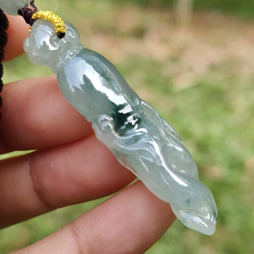 a hand holding a jade pendant