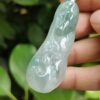 a hand holding a jade pendant