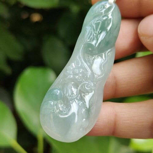 a hand holding a jade pendant