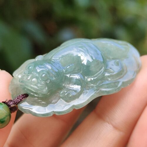 a hand holding a jade pendant