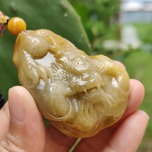 a hand holding a jade pendant