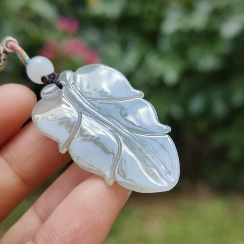 a hand holding a leaf shaped pendant