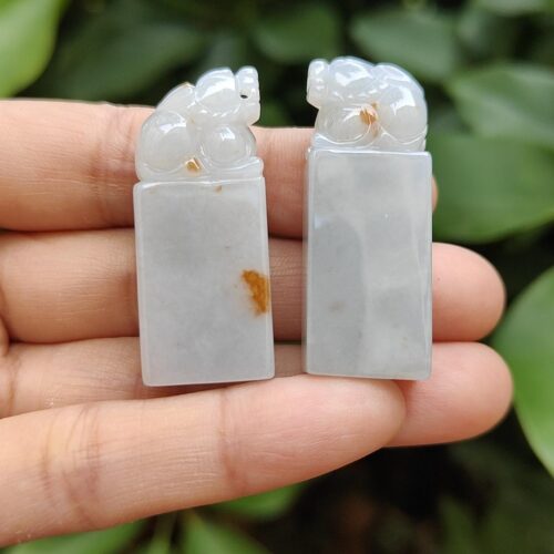 a hand holding a pair of jade carvings