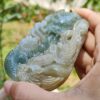 a hand holding a jade pendant