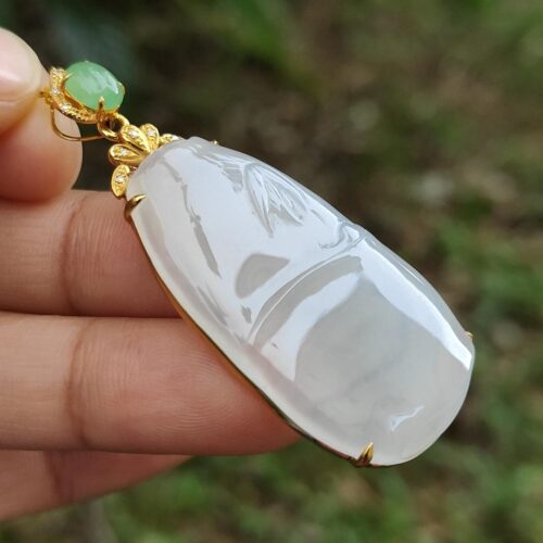 a hand holding a jade pendant