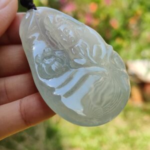 a hand holding a jade pendant
