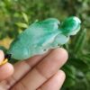 a hand holding a jade fish pendant